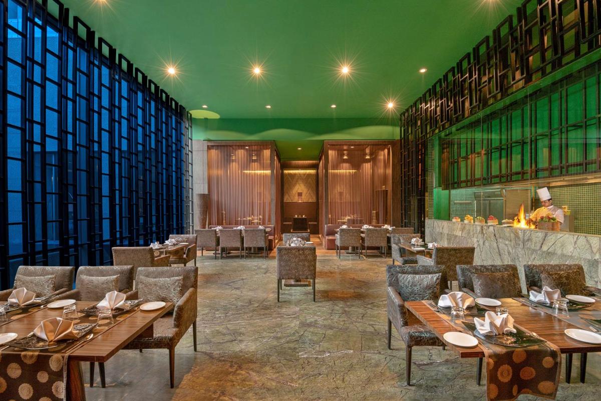 a dining room with wooden tables and chairs at Radisson Blu Hotel Amritsar in Amritsar