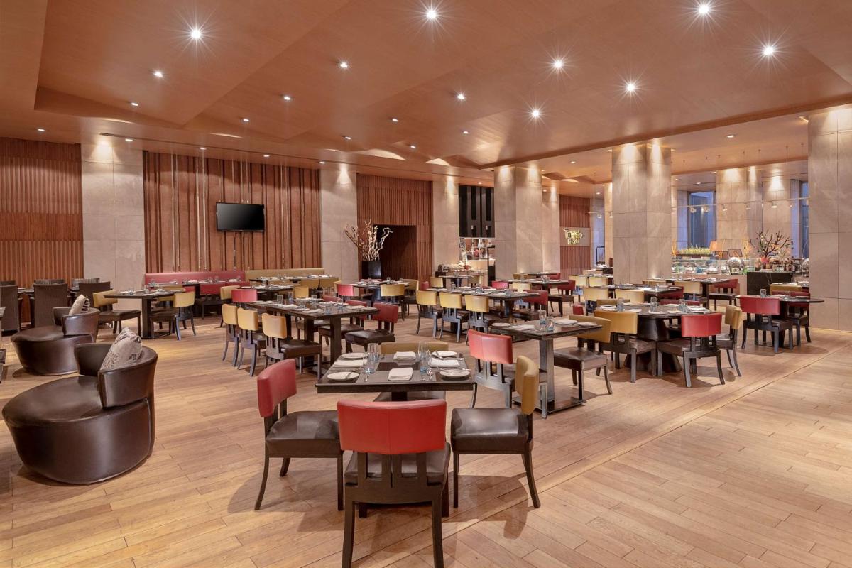 a restaurant with tables and chairs and a flat screen tv at Radisson Blu Hotel Amritsar in Amritsar