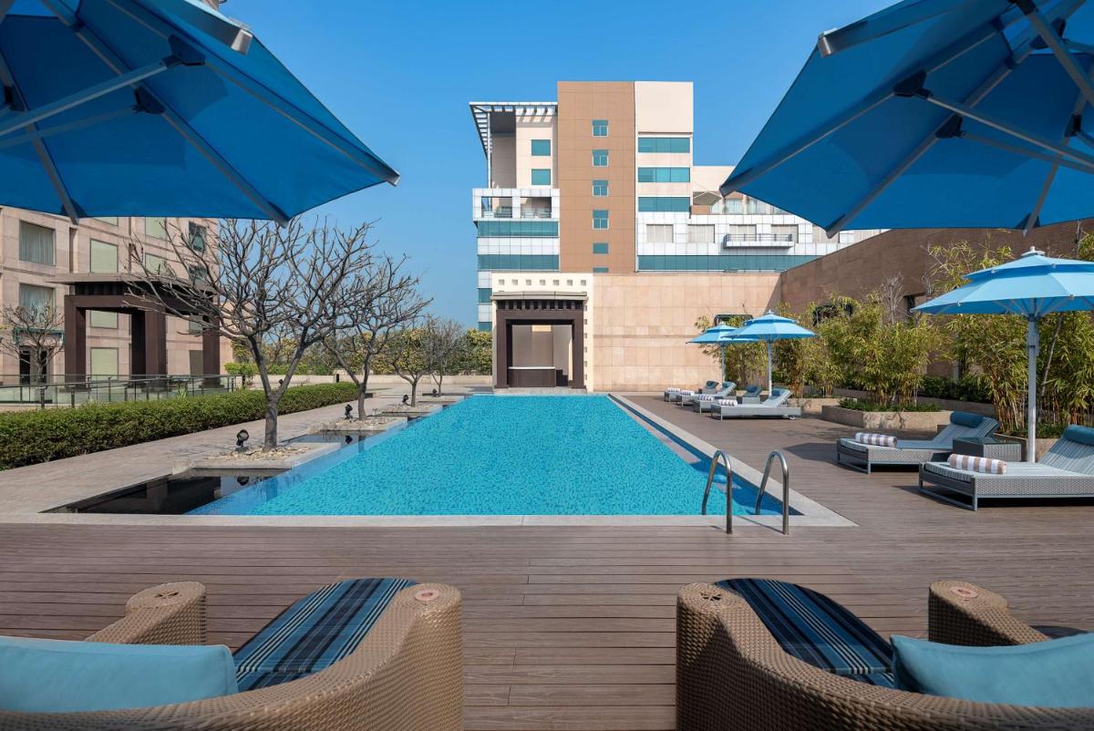 a pool with chairs and umbrellas and a building at Radisson Blu Hotel Amritsar in Amritsar