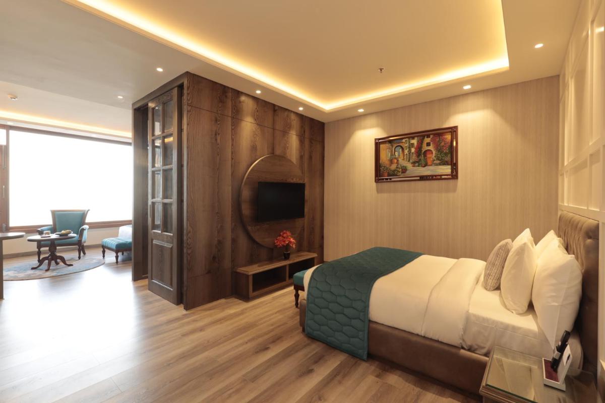 a hotel room with a bed and a living room at WelcomHeritage Elysium Resort & Spa in Shimla