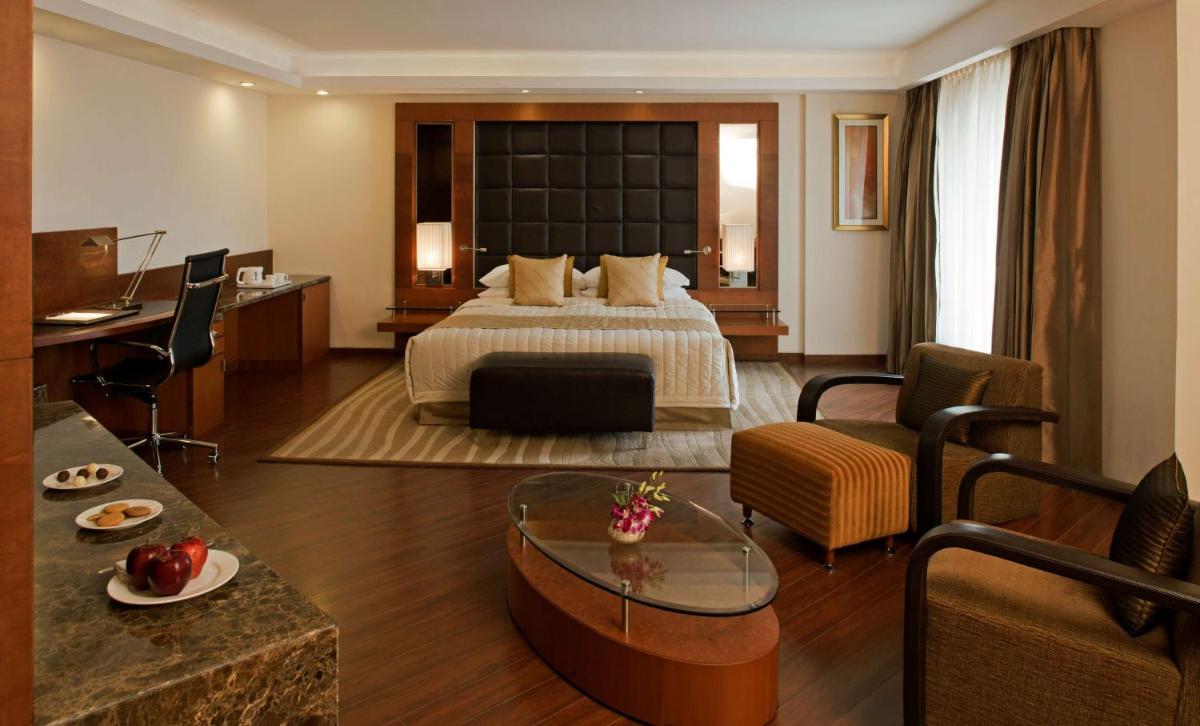 a hotel room with a bed and a living room at Radisson Blu Plaza Delhi Airport in New Delhi a hotel room with a bed and a living room at Radisson Blu Plaza Delhi Airport in New Delhi