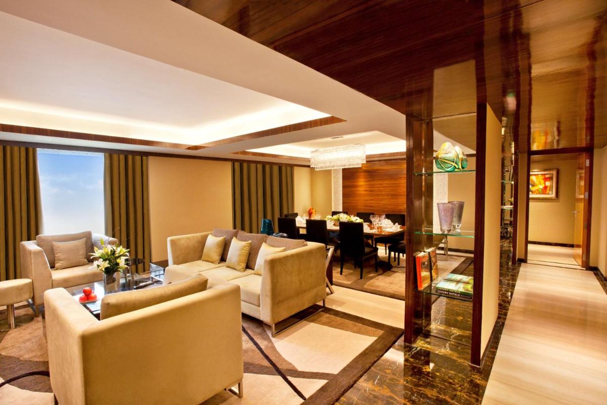 a living room with couches and a dining room at Radisson Blu Plaza Delhi Airport in New Delhi a living room with couches and a dining room at Radisson Blu Plaza Delhi Airport in New Delhi