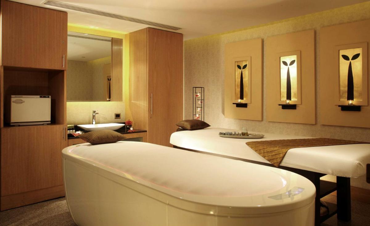 a hotel room with two beds and a bath tub at Radisson Blu Plaza Delhi Airport in New Delhi a hotel room with two beds and a bath tub at Radisson Blu Plaza Delhi Airport in New Delhi