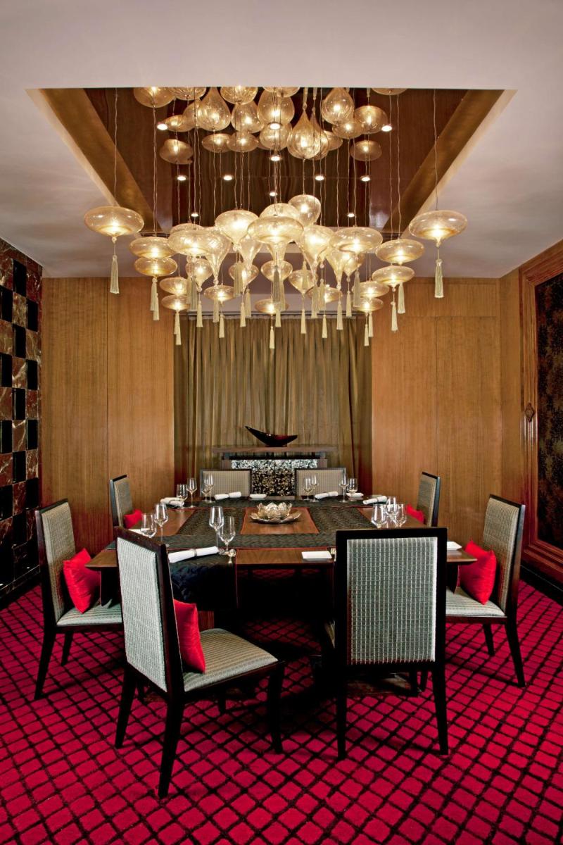 a dining room with a table and chairs and a chandelier at Radisson Blu Plaza Delhi Airport in New Delhi a dining room with a table and chairs and a chandelier at Radisson Blu Plaza Delhi Airport in New Delhi