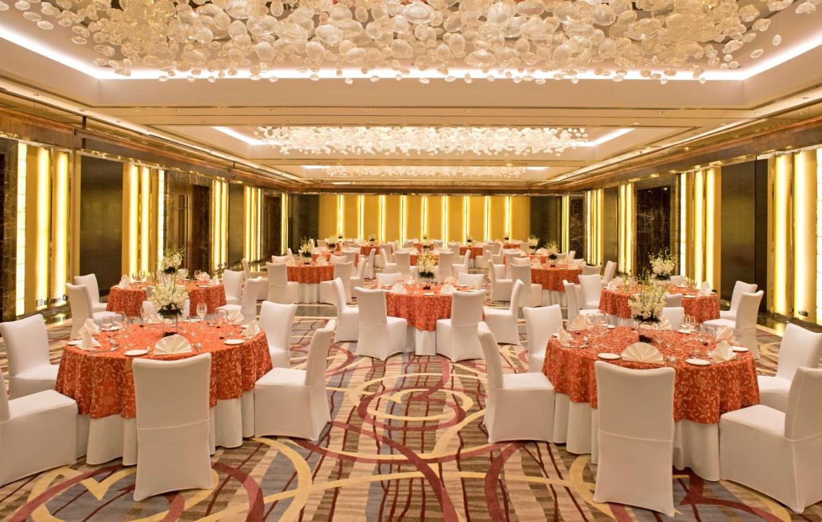 a ballroom with tables and white chairs and a large room at Radisson Blu Plaza Delhi Airport in New Delhi a ballroom with tables and white chairs and a large room at Radisson Blu Plaza Delhi Airport in New Delhi