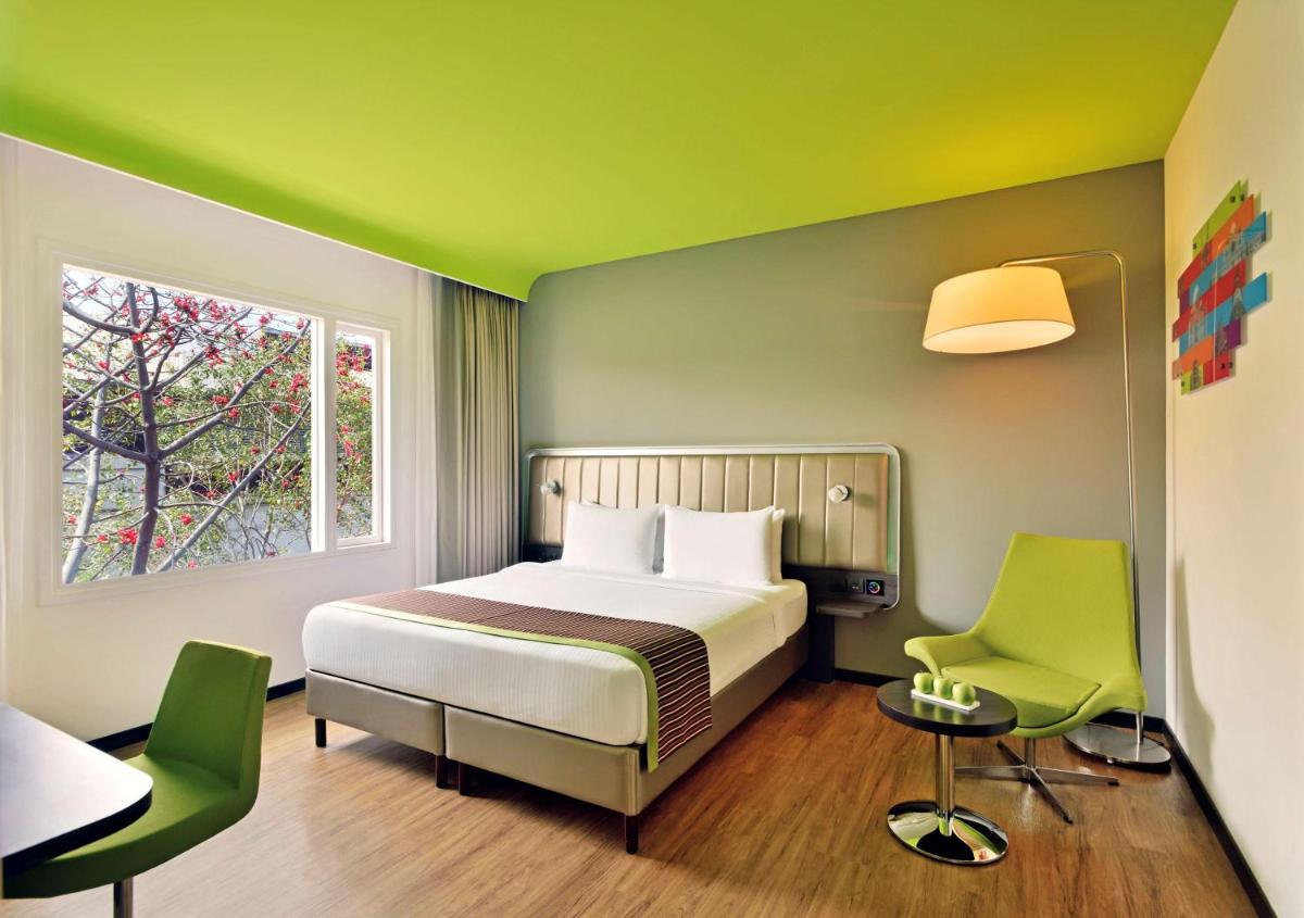 a bedroom with a bed and two green chairs at Park Inn by Radisson,South Delhi in New Delhi a bedroom with a bed and two green chairs at Park Inn by Radisson,South Delhi in New Delhi