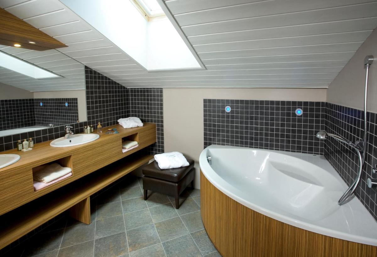 une salle de bain avec une grande baignoire et un lavabo dans l'établissement Le Calgary, aux Saisies