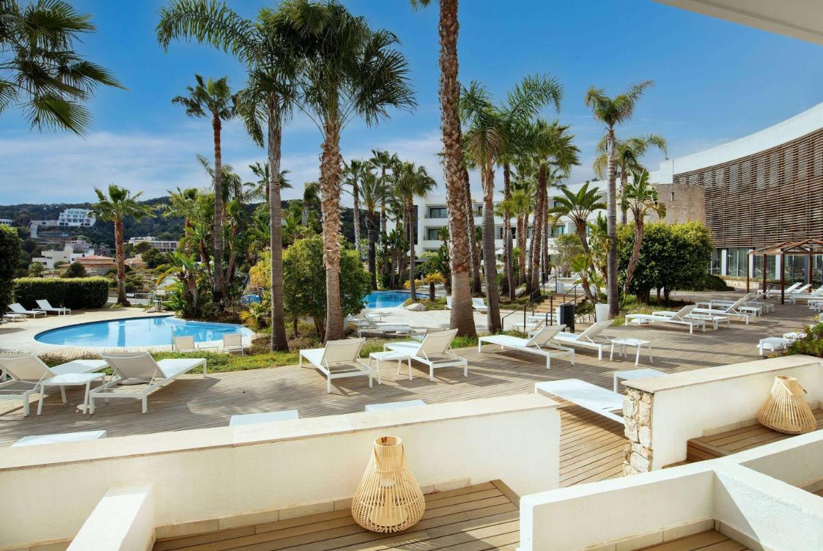 un patio al aire libre con piscina y palmeras en Eurostars Sitges, en Sitges