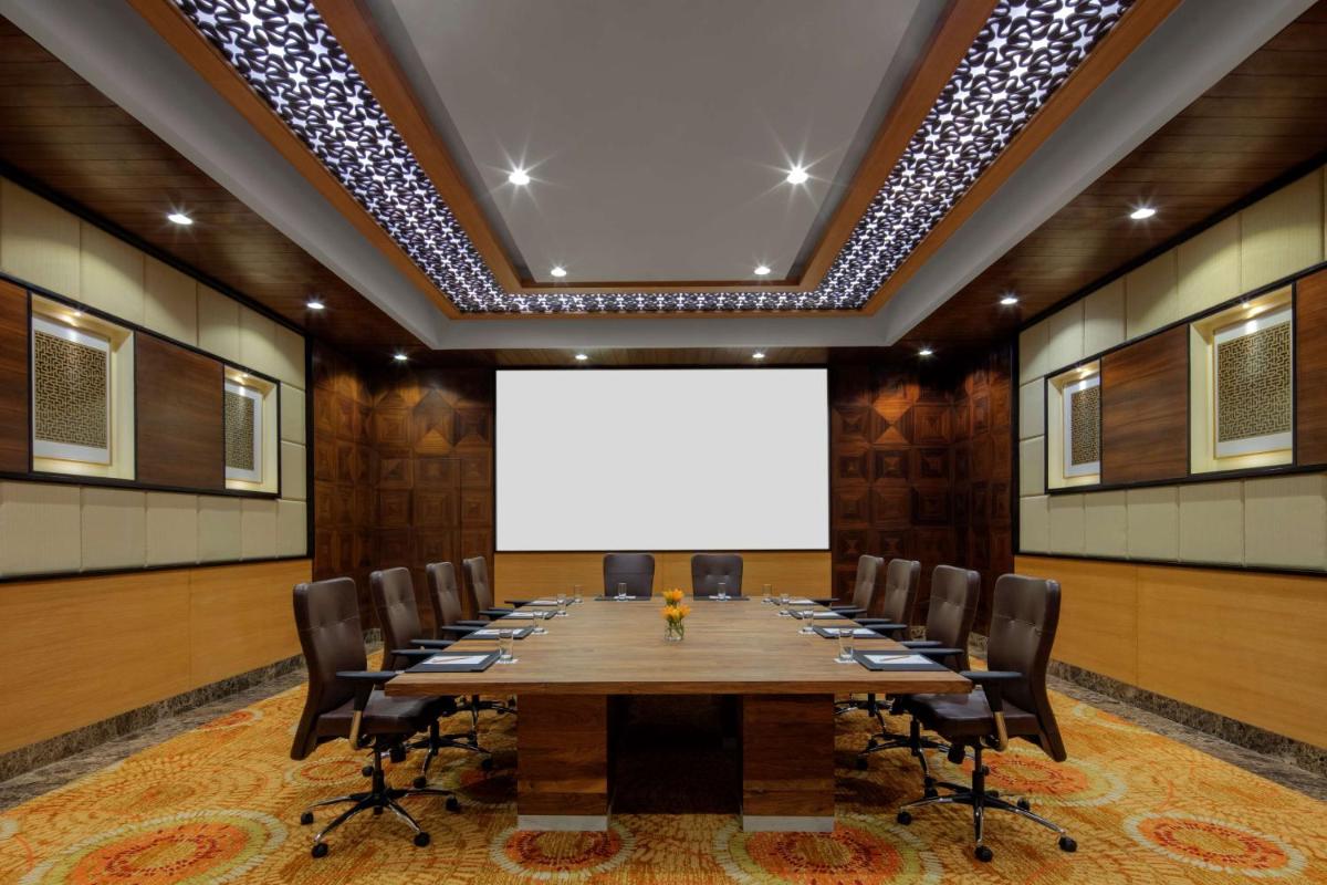 a conference room with a large table and a white screen at Radisson Jodhpur in Jodhpur