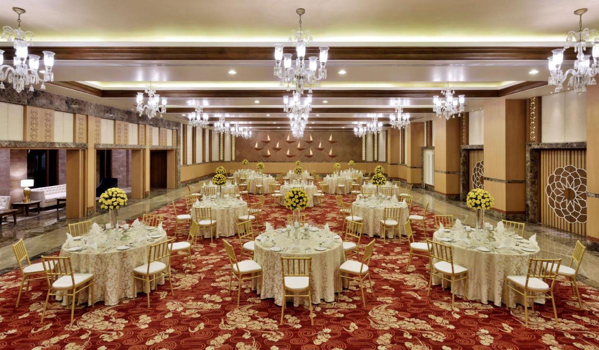 a banquet hall with white tables and chairs and chandeliers at Radisson Jodhpur in Jodhpur