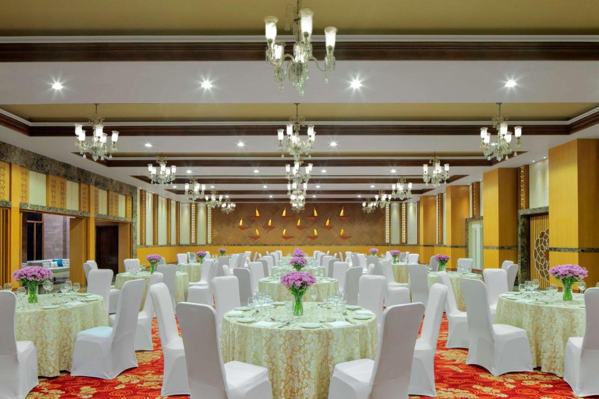 a banquet hall with white tables and chairs and chandeliers at Radisson Jodhpur in Jodhpur +83 photos