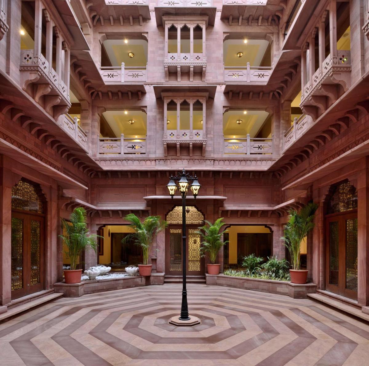 a large building with a courtyard with palm trees at Radisson Jodhpur in Jodhpur