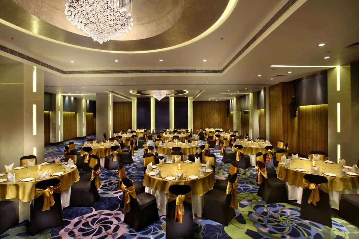 a banquet hall with tables and chairs and a chandelier at Park Plaza Shahdara in New Delhi a banquet hall with tables and chairs and a chandelier at Park Plaza Shahdara in New Delhi