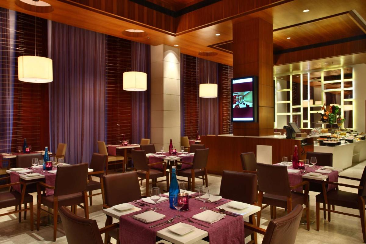 a restaurant with tables and chairs and a bar at Park Plaza Shahdara in New Delhi a restaurant with tables and chairs and a bar at Park Plaza Shahdara in New Delhi