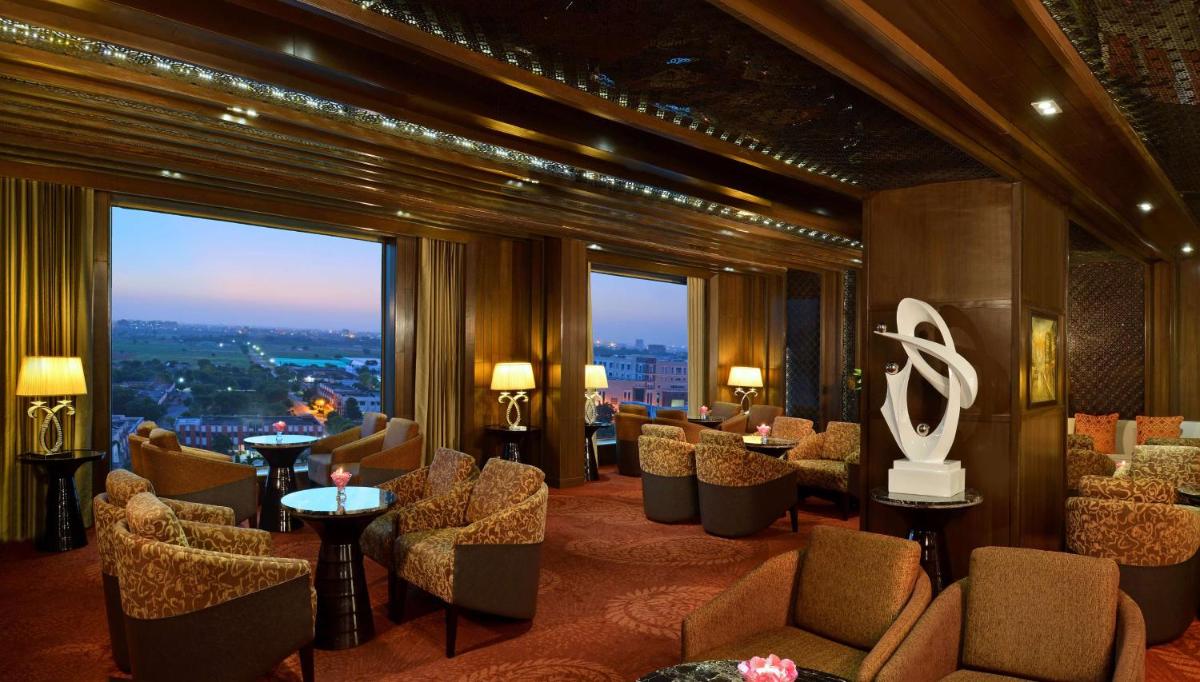 a hotel lobby with chairs and tables and a large window at Radisson Blu Jaipur in Jaipur