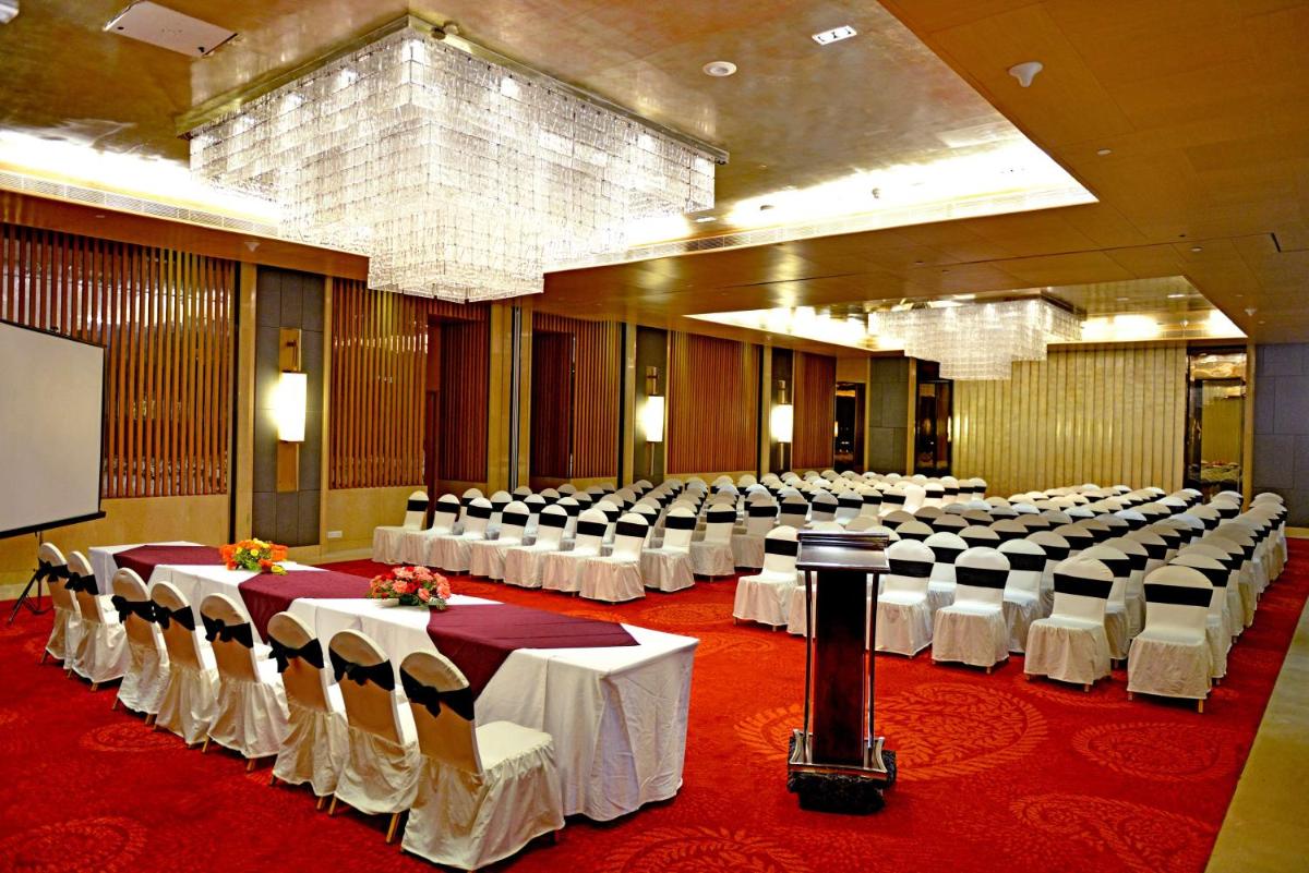 a large banquet hall with white tables and chairs at Radisson Blu Jaipur in Jaipur