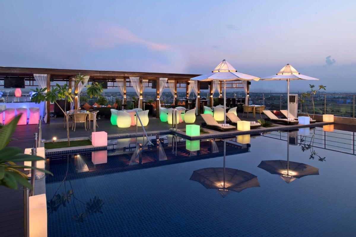 a hotel swimming pool with chairs and umbrellas at Radisson Blu Jaipur in Jaipur