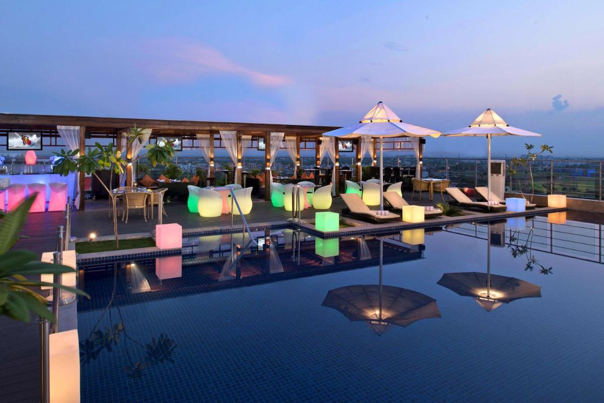 a swimming pool with chairs and umbrellas on a building at Radisson Blu Jaipur in Jaipur