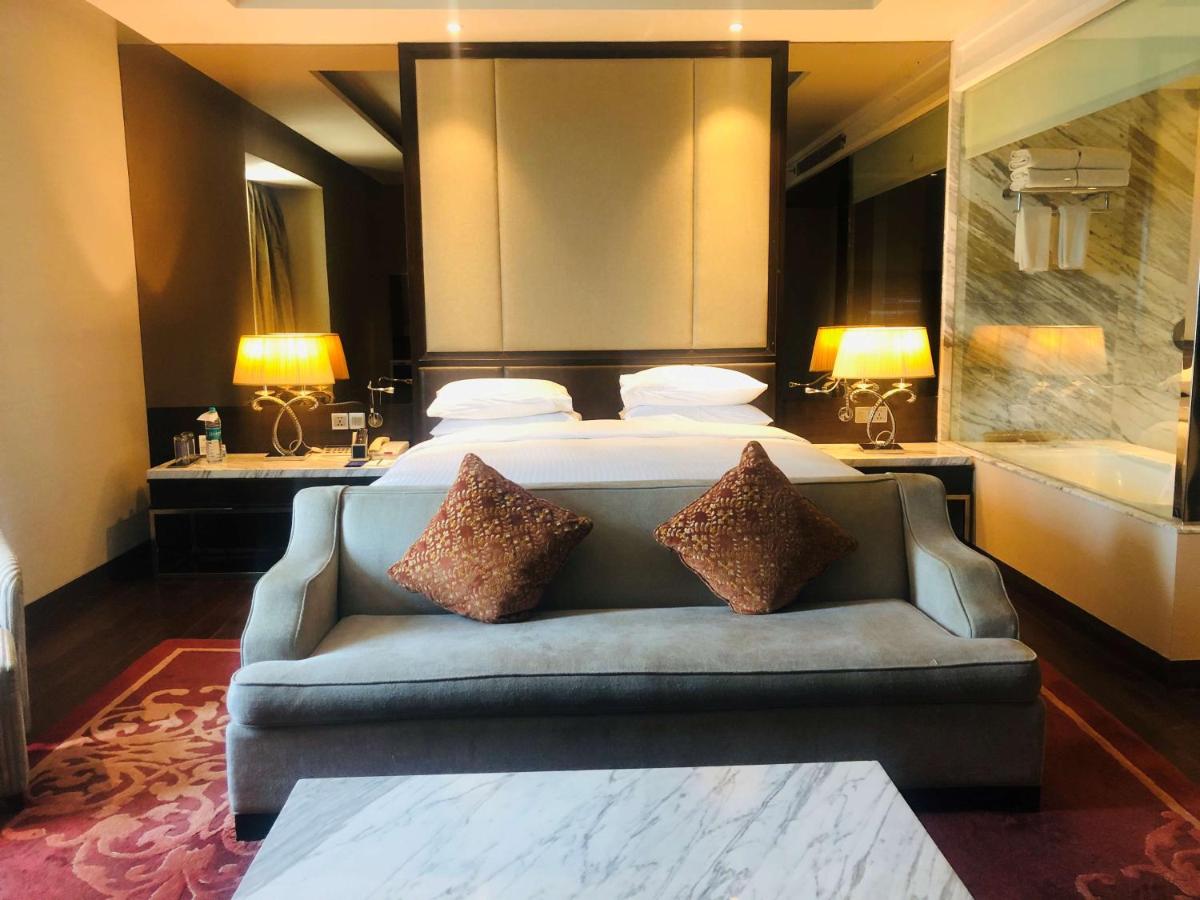 a bedroom with a bed and a couch with two pillows at Radisson Blu Jaipur in Jaipur