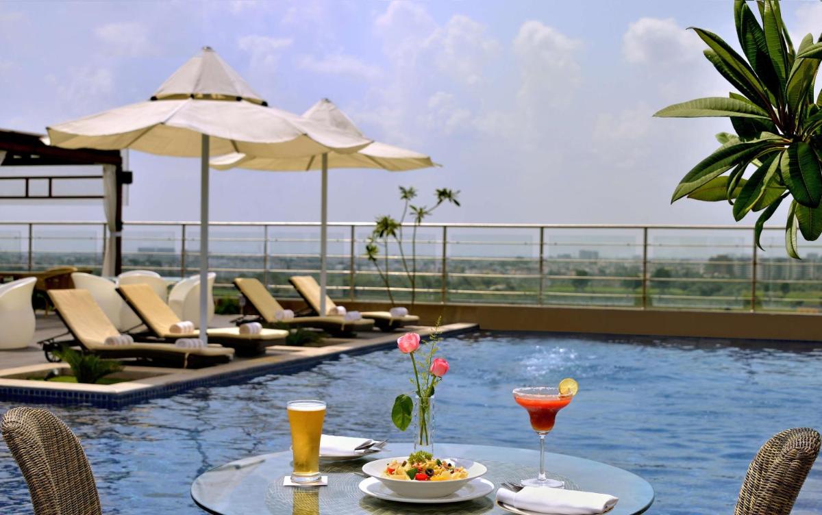 a table with a plate of food and drinks on a pool at Radisson Blu Jaipur in Jaipur