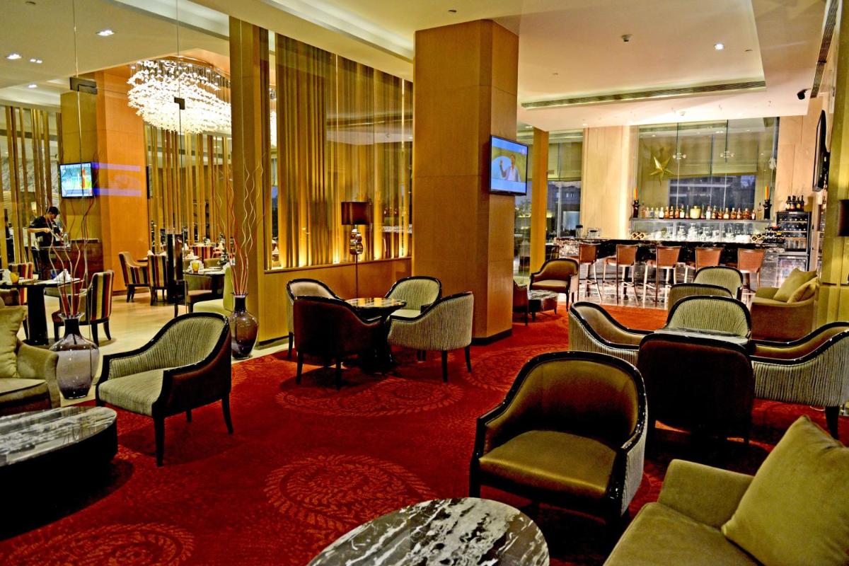 a lobby of a hotel with chairs and a bar at Radisson Blu Jaipur in Jaipur