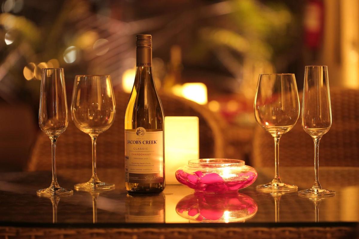 a bottle of wine and four wine glasses on a table at Radisson Blu Jaipur in Jaipur