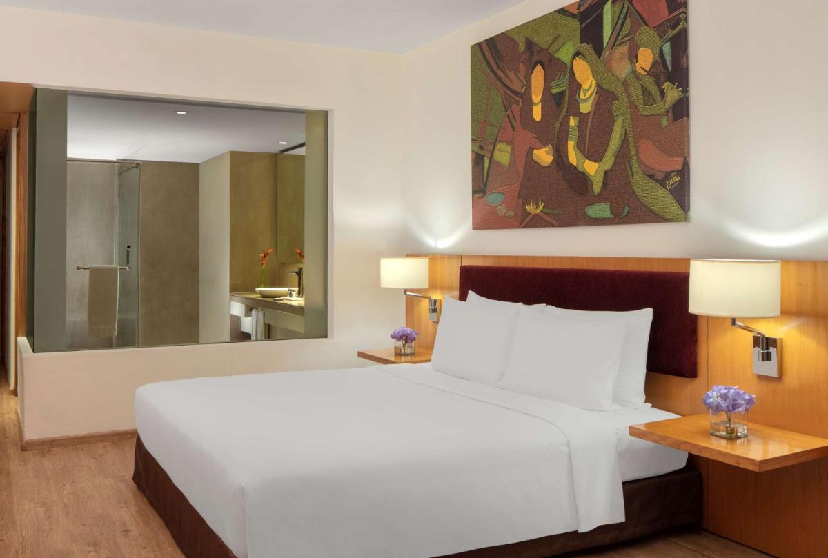 a bedroom with a white bed and a large mirror at Radisson Blu Plaza Hotel Hyderabad Banjara Hills in Hyderabad a bedroom with a white bed and a large mirror at Radisson Blu Plaza Hotel Hyderabad Banjara Hills in Hyderabad