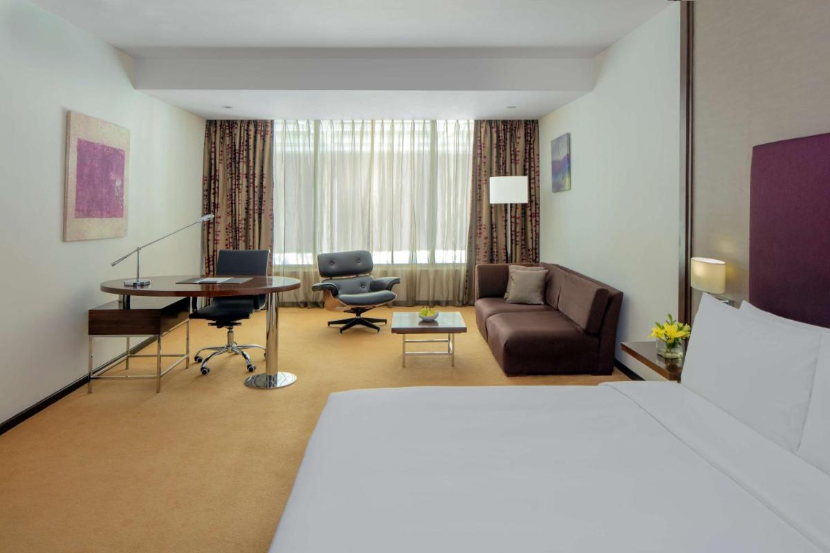 a hotel room with a bed and a living room at Radisson Blu Plaza Hotel Hyderabad Banjara Hills in Hyderabad a hotel room with a bed and a living room at Radisson Blu Plaza Hotel Hyderabad Banjara Hills in Hyderabad