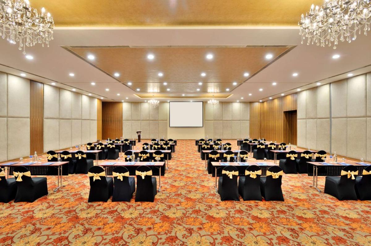 a banquet hall with tables and chairs and a screen at Radisson Blu Plaza Hotel Hyderabad Banjara Hills in Hyderabad a banquet hall with tables and chairs and a screen at Radisson Blu Plaza Hotel Hyderabad Banjara Hills in Hyderabad