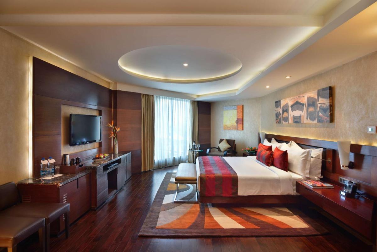 a hotel room with a bed and a television at Radisson Blu Kaushambi Delhi NCR in Ghaziabad