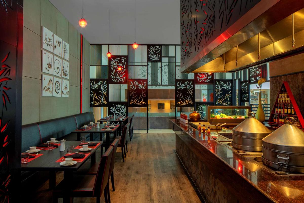 a restaurant with long tables and a buffet at Radisson Blu Plaza Hotel Hyderabad Banjara Hills in Hyderabad a restaurant with long tables and a buffet at Radisson Blu Plaza Hotel Hyderabad Banjara Hills in Hyderabad