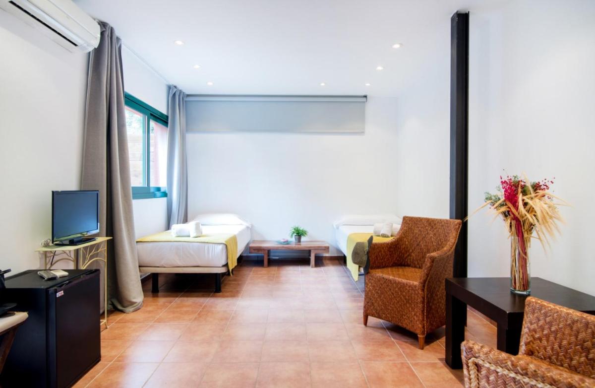 Una sala de estar con un sofá y un televisor. en Mas Ses Vinyes - Adults Only, en Begur