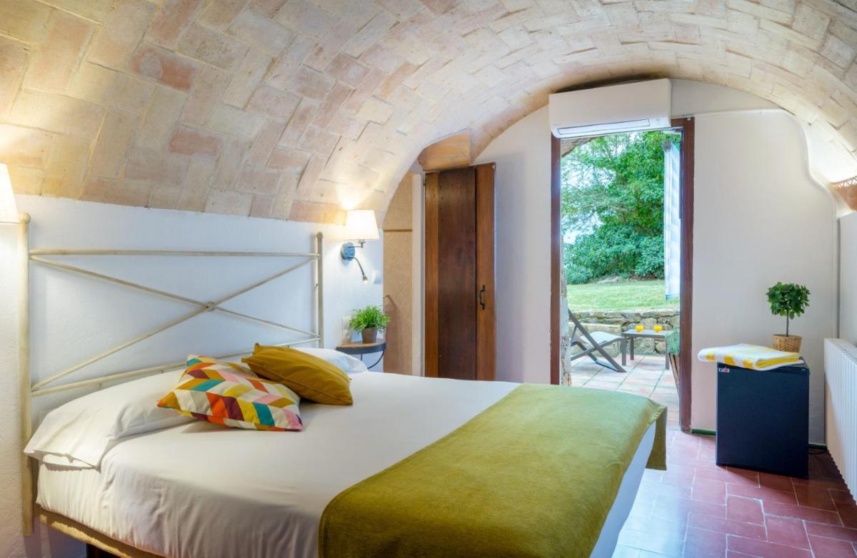 Un dormitorio con una cama grande con una pared de piedra. en Mas Ses Vinyes - Adults Only, en Begur 122 fotos más