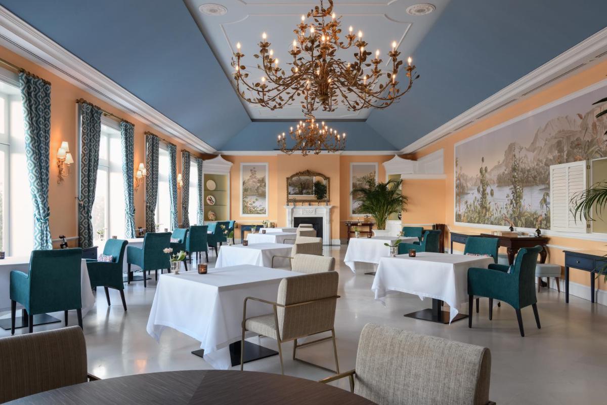 um restaurante com mesas e cadeiras brancas e um lustre em The Yeatman em Vila Nova de Gaia