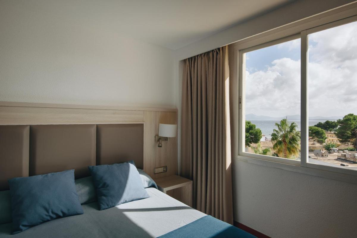 Un dormitorio con una cama y una ventana grande. en Hotel Ivory Playa Sports & Spa, en Puerto de Alcudia