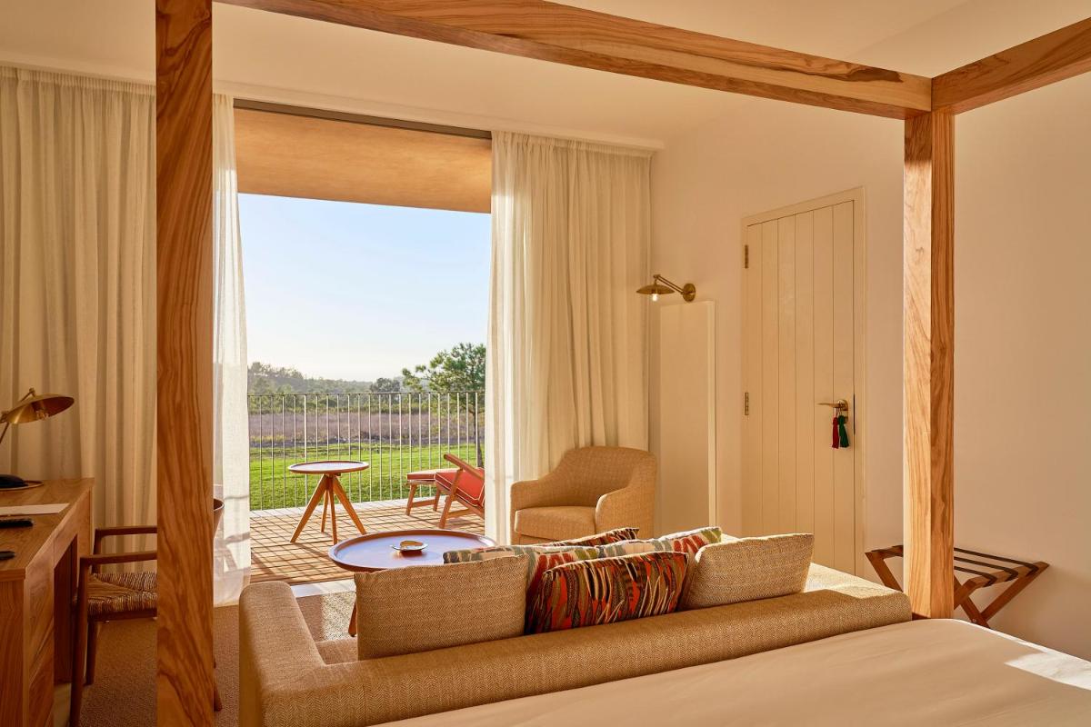 um quarto com uma cama com vista para um pátio em Praia do Canal Nature Retreat - Small Luxury Hotels of the World em Aljezur