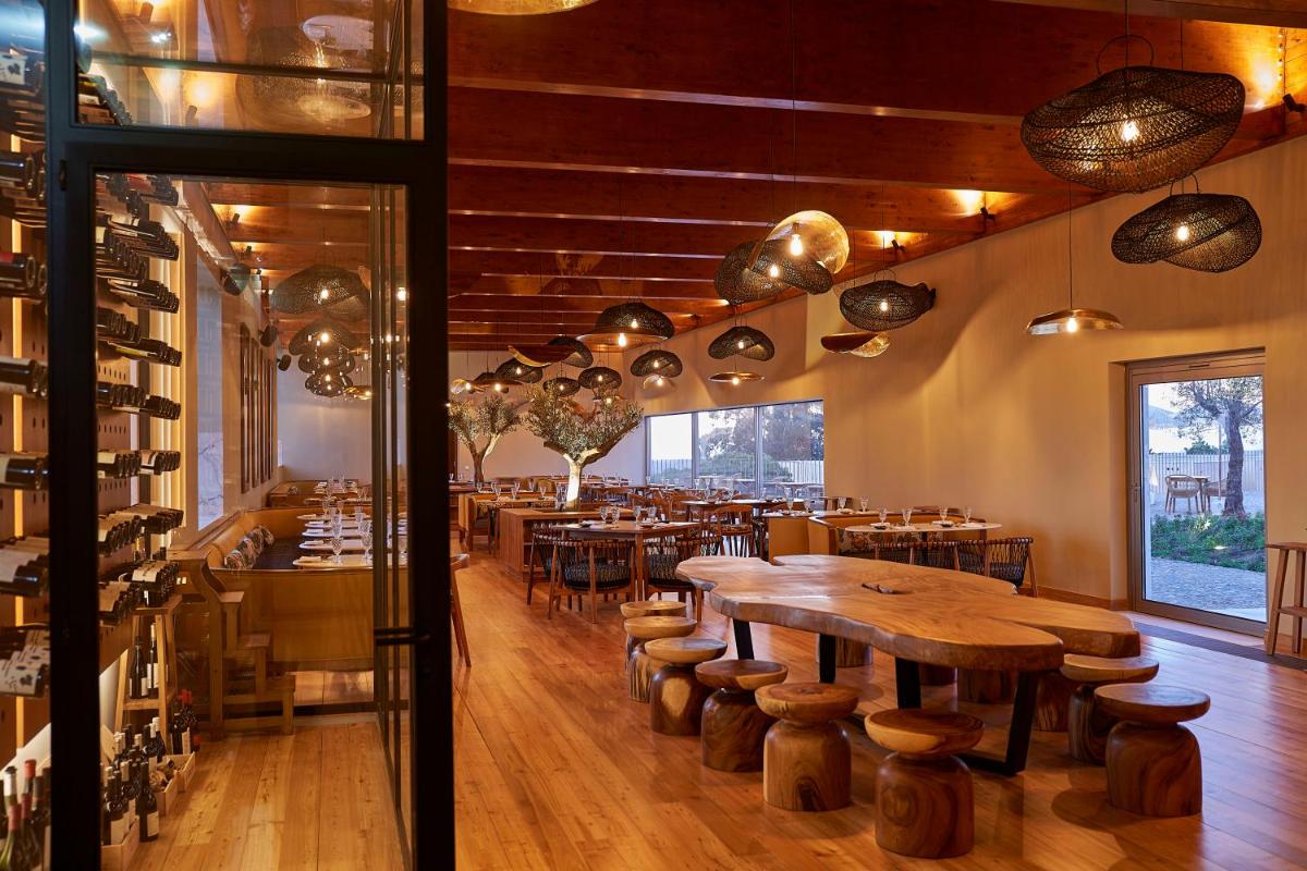 um restaurante com mesas e cadeiras em uma sala em Praia do Canal Nature Retreat - Small Luxury Hotels of the World em Aljezur