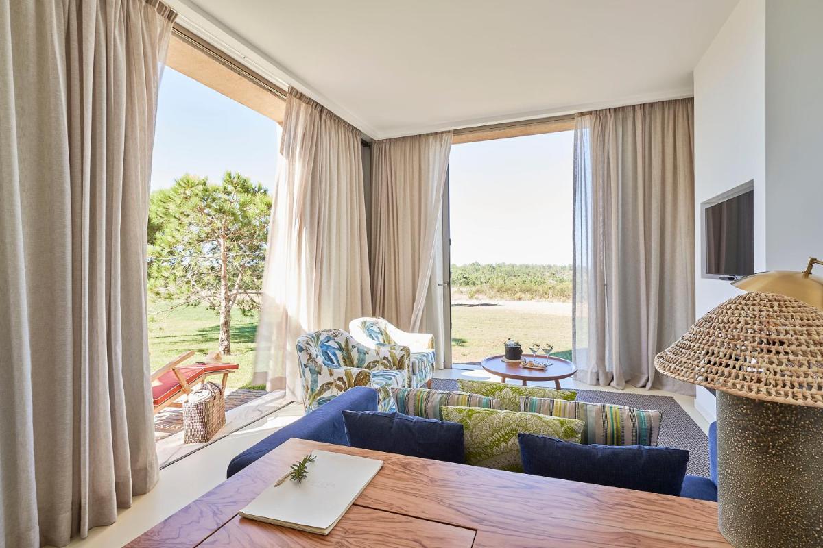 uma sala de estar com um sofá azul e uma grande janela em Praia do Canal Nature Retreat - Small Luxury Hotels of the World em Aljezur