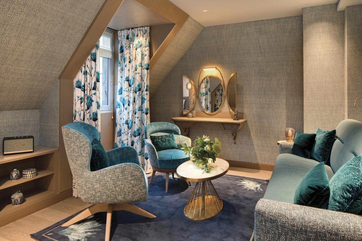 un salon avec des chaises bleues et une table dans l'établissement La Demeure Montaigne, à Paris
