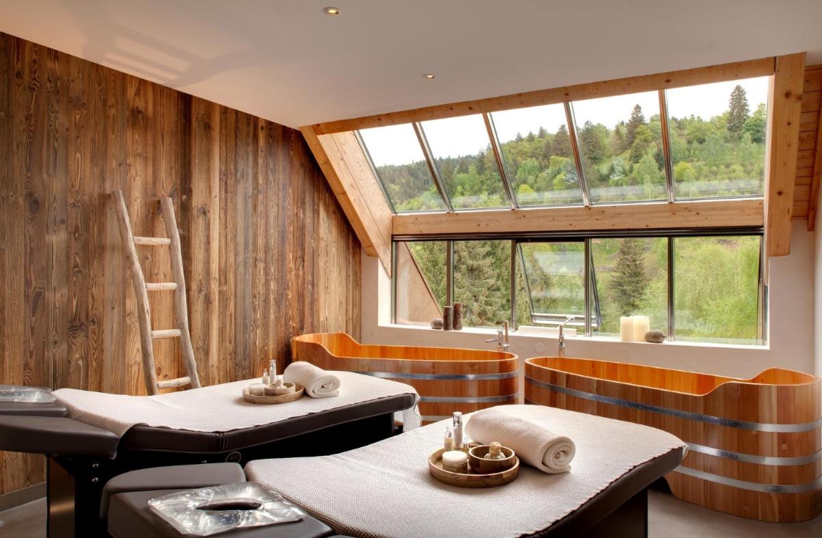 un restaurant avec deux tables et une grande fenêtre dans l'établissement LA CHENEAUDIÈRE - Hôtel Spa - Relais & Châteaux - Restaurant étoilé, à Colroy-la-Roche 37 autres photos