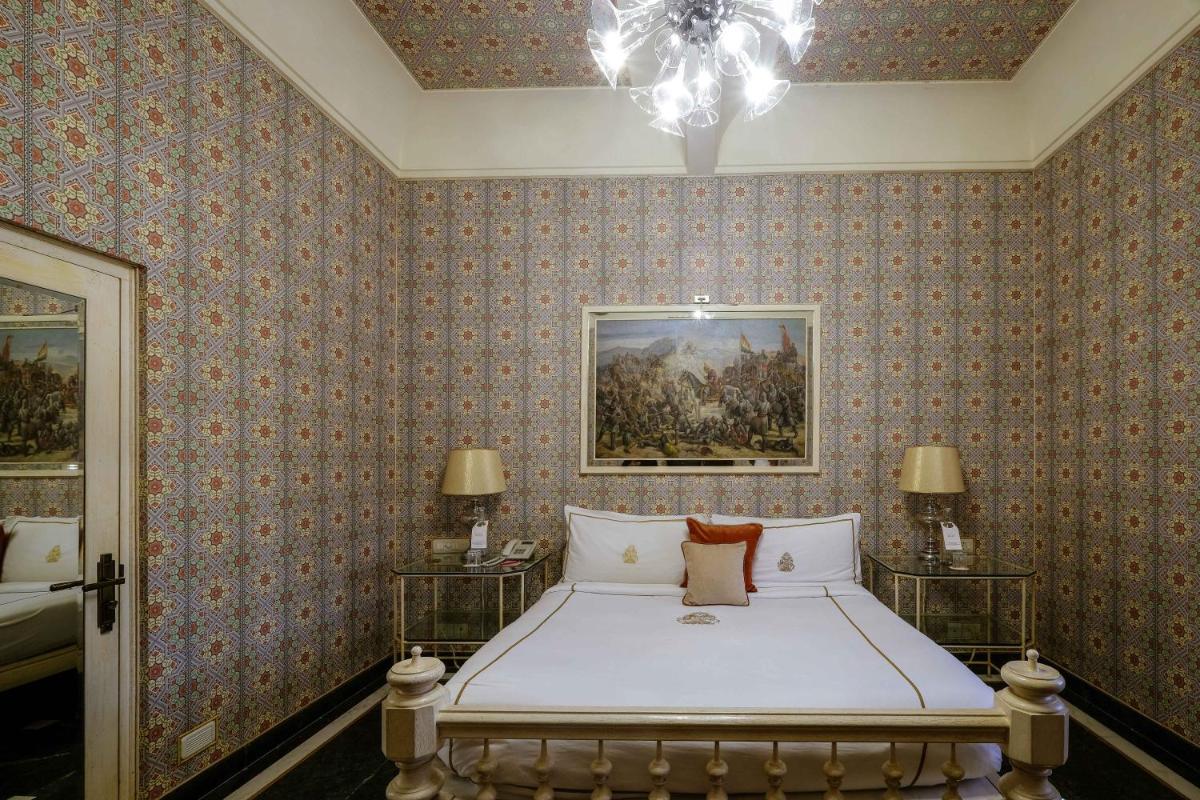 a bedroom with a bed and a painting on the wall at Rajmahal Palace RAAS in Jaipur