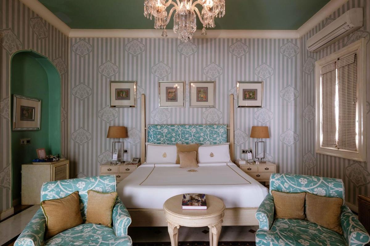 a bedroom with a large bed and two chairs at Rajmahal Palace RAAS in Jaipur