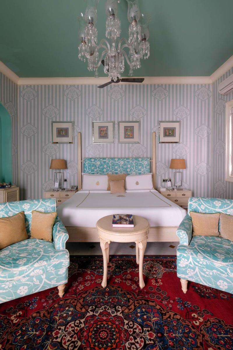 a bedroom with a bed and two chairs and a table at Rajmahal Palace RAAS in Jaipur