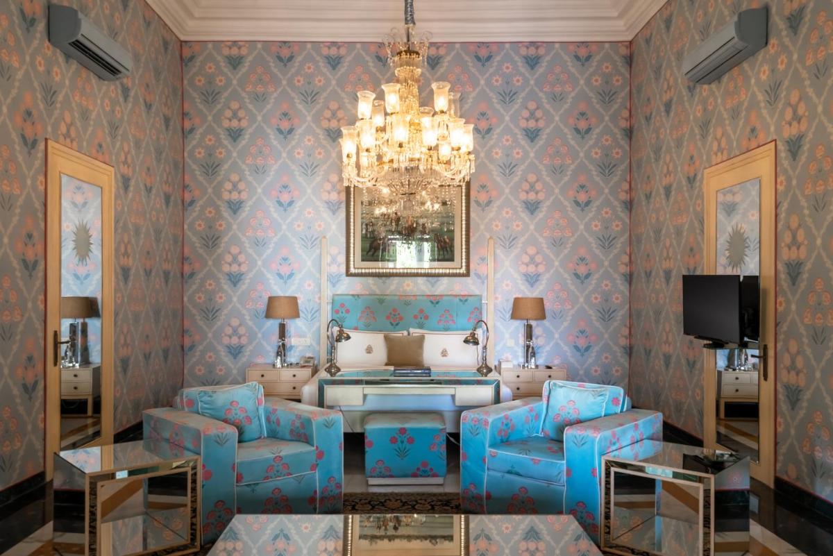 a living room with blue chairs and a chandelier at Rajmahal Palace RAAS in Jaipur