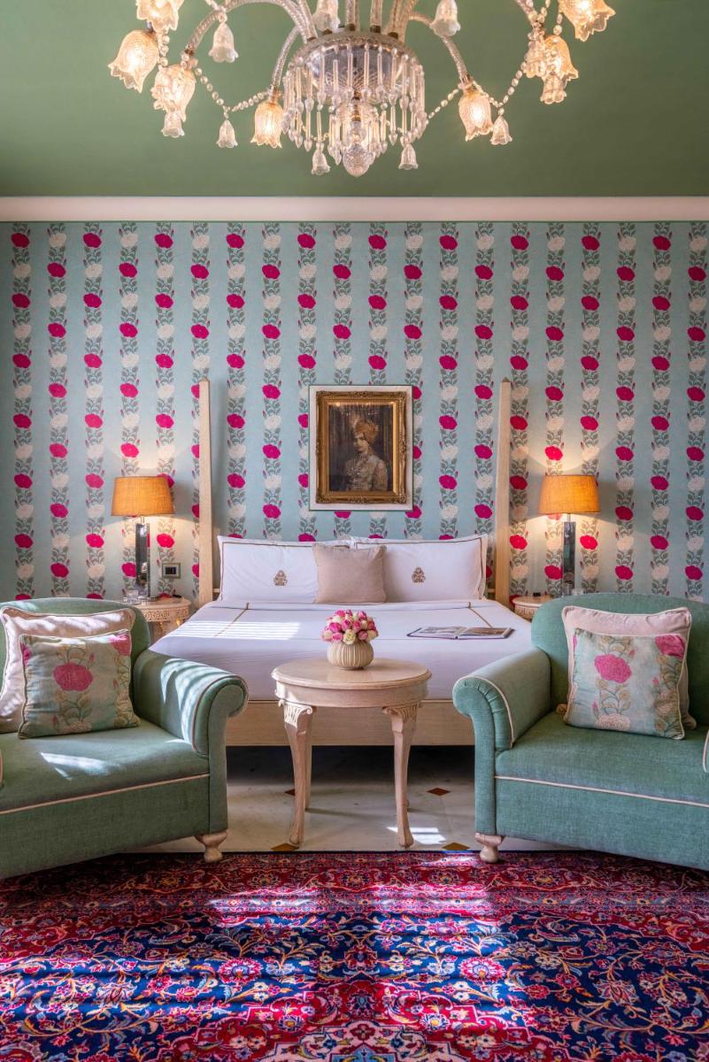 a bedroom with a bed and two chairs and a chandelier at Rajmahal Palace RAAS in Jaipur