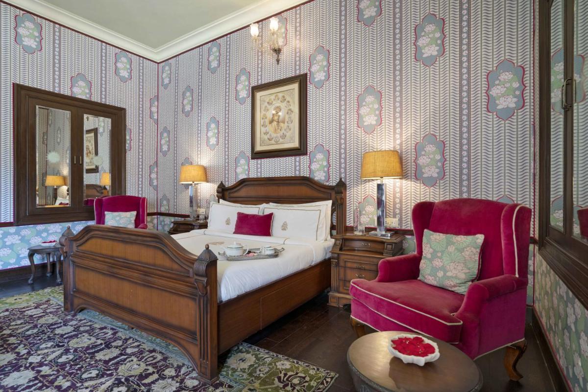 a bedroom with a bed and a chair at Rajmahal Palace RAAS in Jaipur