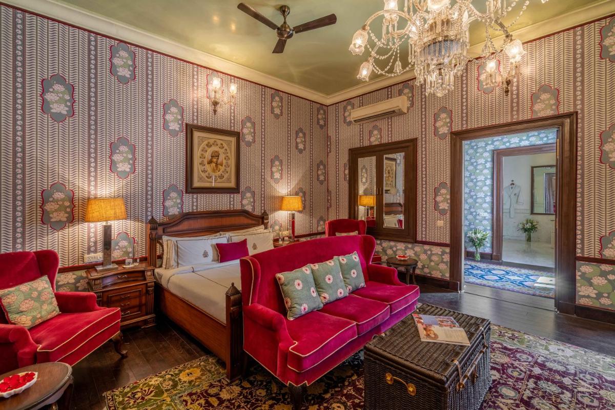 a bedroom with a bed and two red chairs at Rajmahal Palace RAAS in Jaipur
