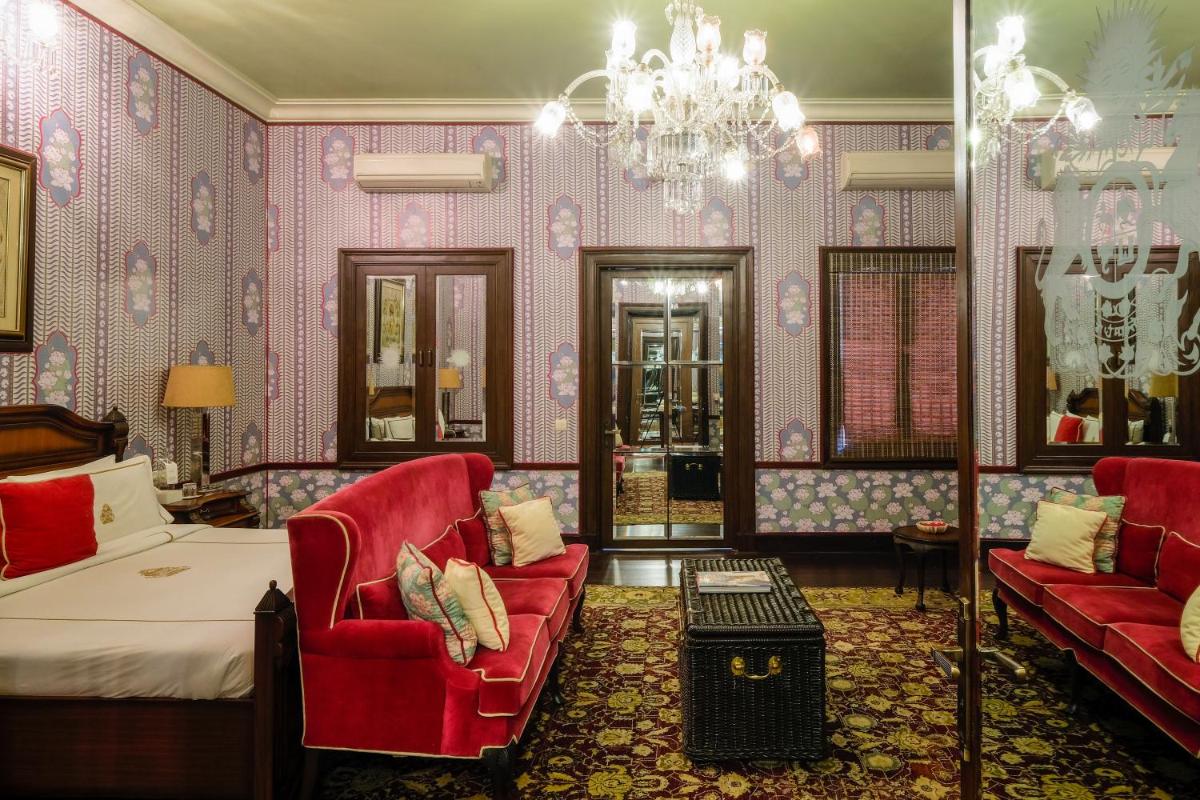 a bedroom with a bed and a couch and a chandelier at Rajmahal Palace RAAS in Jaipur