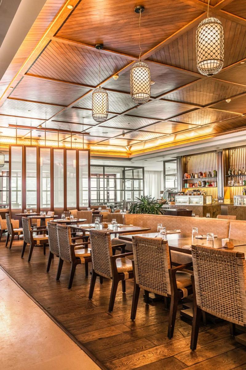 a dining room with wooden tables and chairs at Grand Hyatt Goa in Panaji a dining room with wooden tables and chairs at Grand Hyatt Goa in Panaji