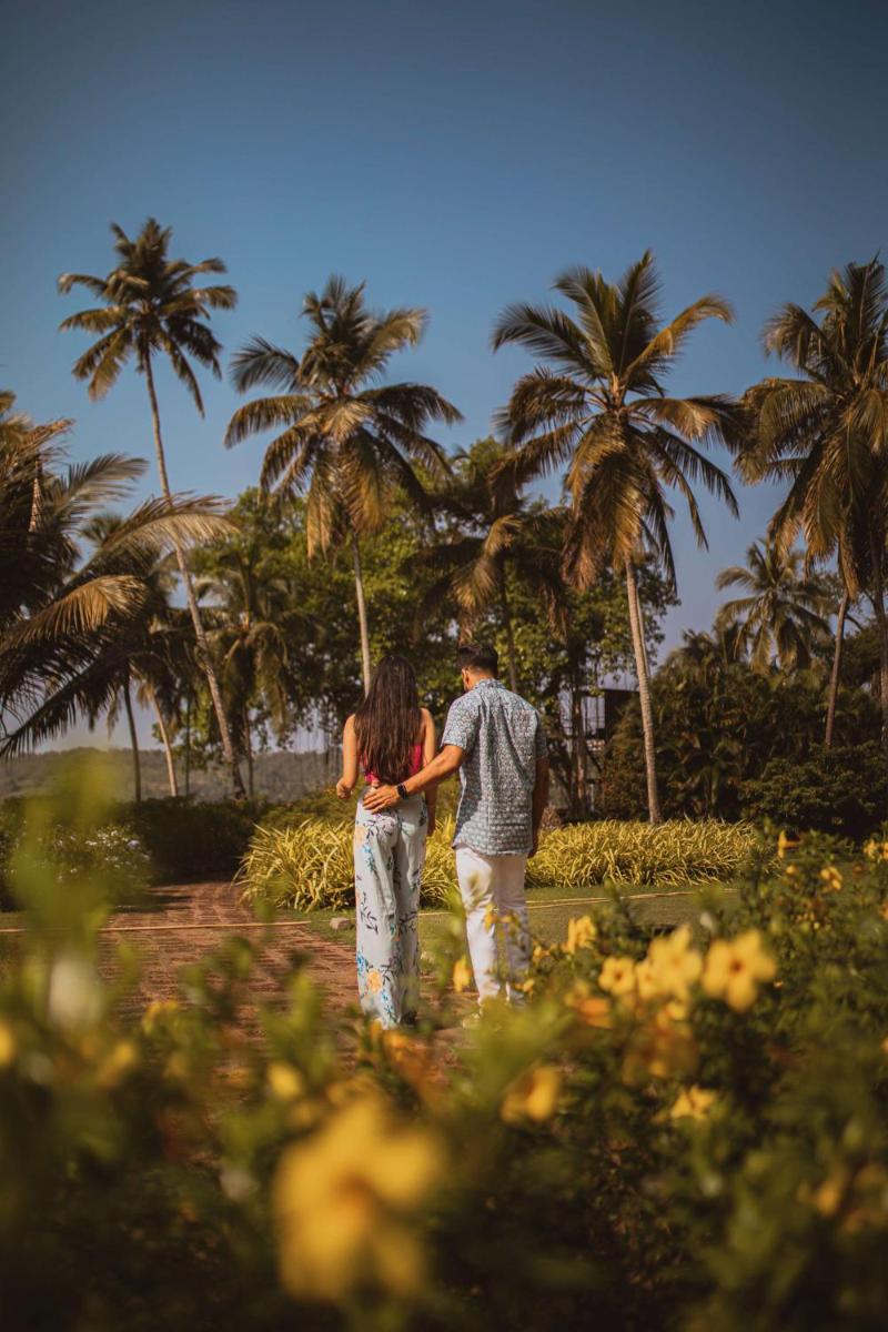 a man and woman standing in front of palm trees at Grand Hyatt Goa in Panaji a man and woman standing in front of palm trees at Grand Hyatt Goa in Panaji